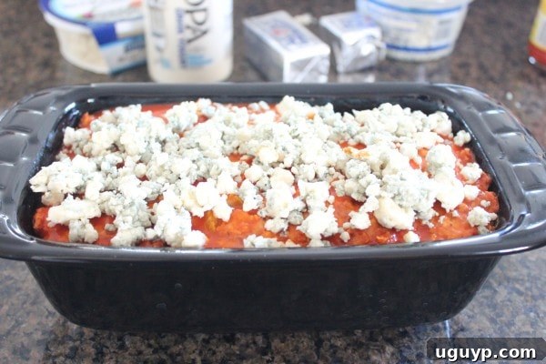 blue cheese crumbles on top of a meatloaf in a loaf pan