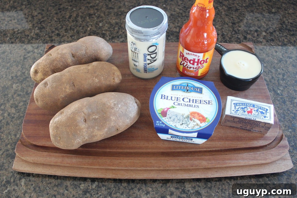 Buffalo Blue Cheese Mashed Potato Ingredients - A flat lay of fresh russet potatoes, butter, milk, buffalo sauce, blue cheese dressing, and blue cheese crumbles.