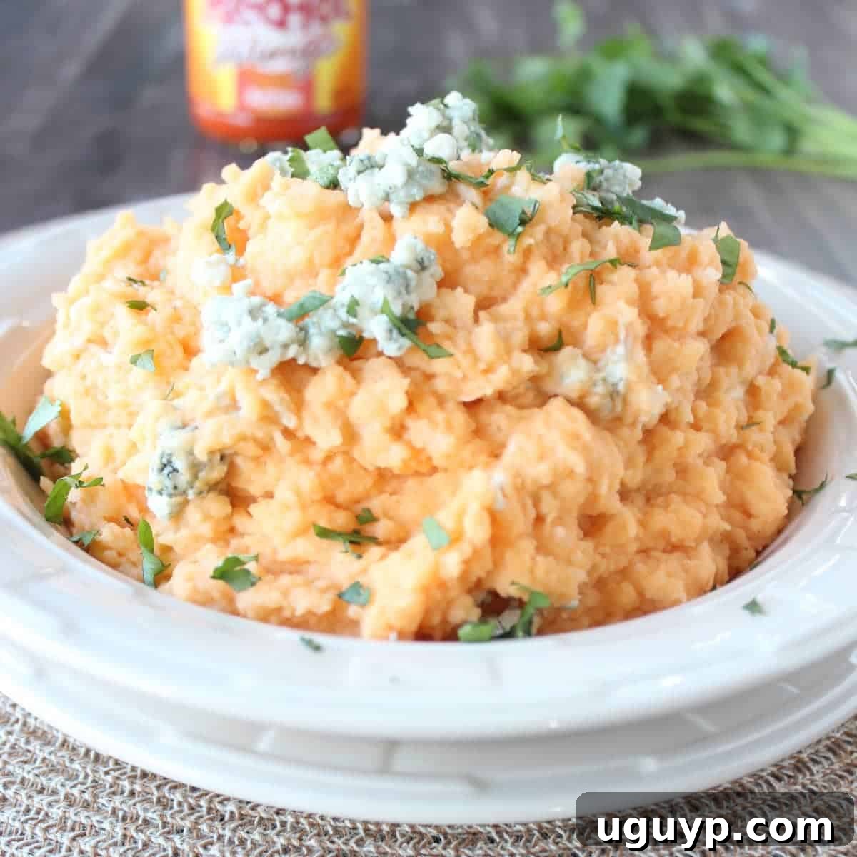 Buffalo Blue Cheese Mashed Potatoes - A close-up of the finished mashed potatoes in a serving dish, topped with melted blue cheese and a swirl of buffalo sauce.