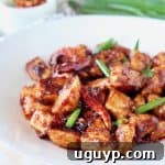 Gluten-free General Tso Chicken with red chilies and green onions on white plate, perfect for dinner.