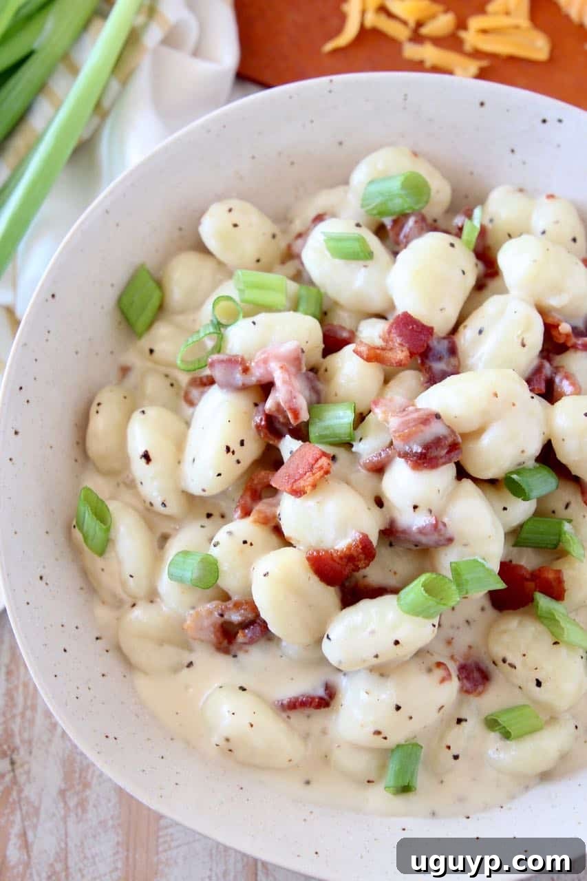 Overhead image of gnocchi in bowl with cream sauce and bacon bits