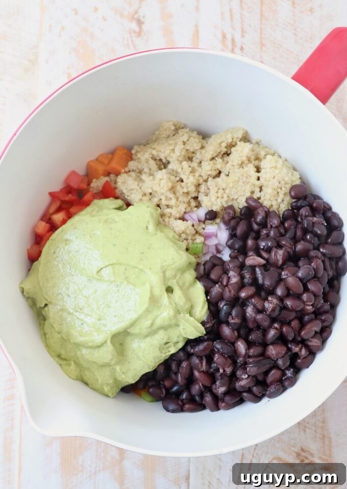 Black beans, cooked quinoa, and diced vegetables in a mixing bowl, ready for the avocado dressing