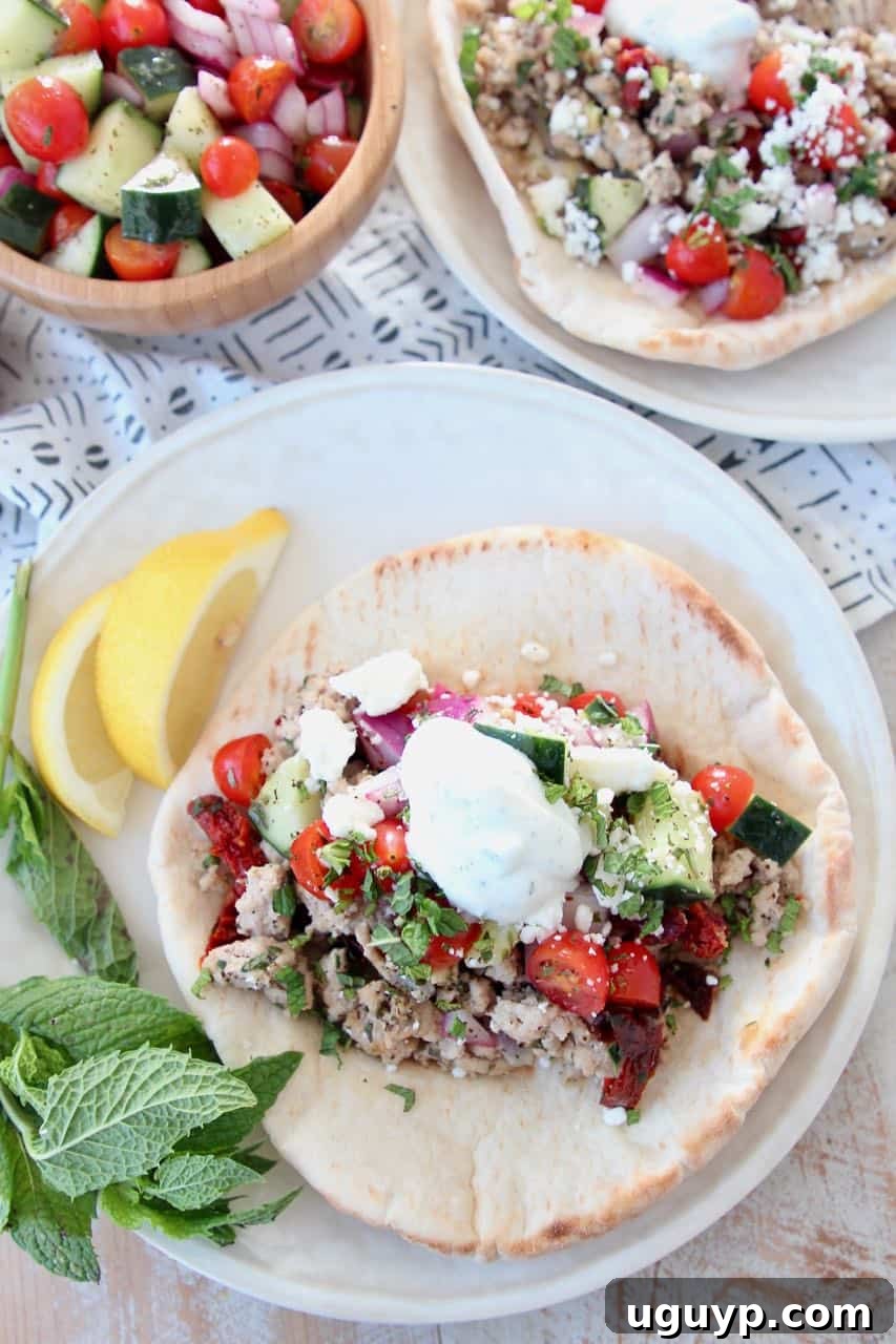 Ground turkey tacos in pita bread on plate, topped with tzatziki sauce