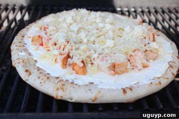 Buffalo Chicken Dip Pizza perfectly cooking on an outdoor grill, with cheese melting and bubbling.