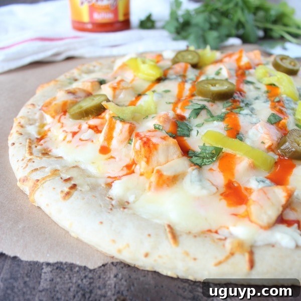 Finished Buffalo Chicken Dip Pizza, garnished with melted cheese, buffalo chicken, pepperoncinis, and jalapeños, ready to serve.