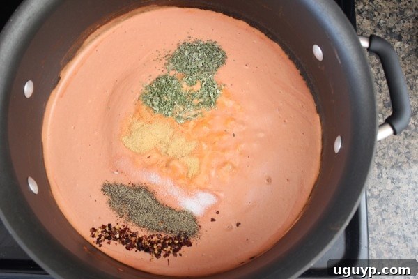 Adding spices to the creamy tomato sauce