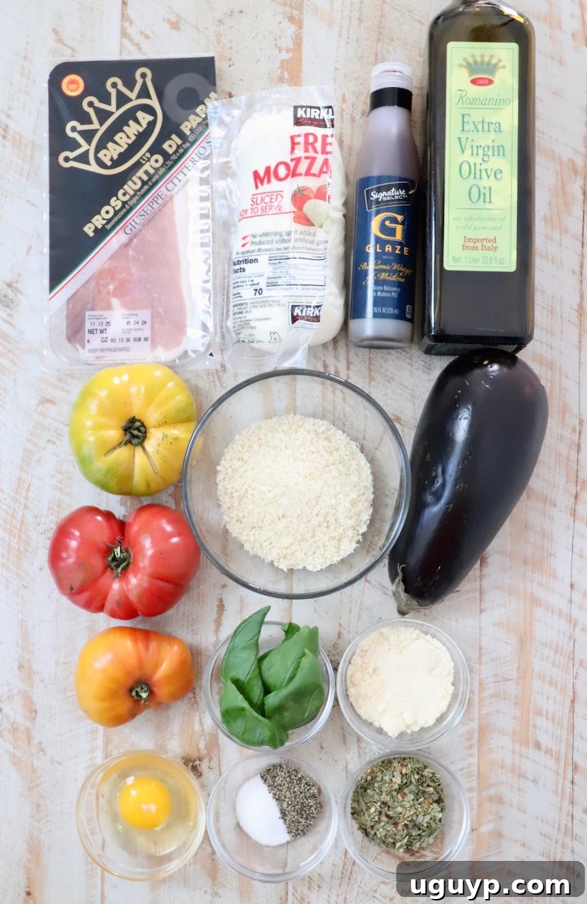 Assorted ingredients for an Italian dish on a wooden surface: eggplant, colorful heirloom tomatoes, prosciutto, mozzarella, panko breadcrumbs, olive oil, basil, egg, and seasonings.