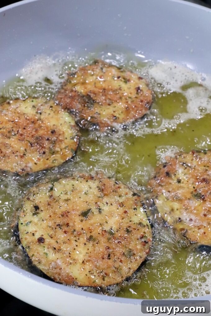breaded slices of eggplant frying in oil in a pan