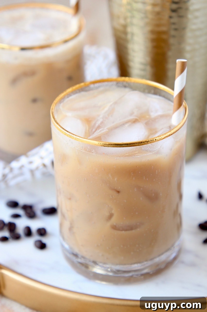 Long Island Iced Coffee cocktail in gold rimmed glass with gold and white striped straw, garnished with coffee beans.