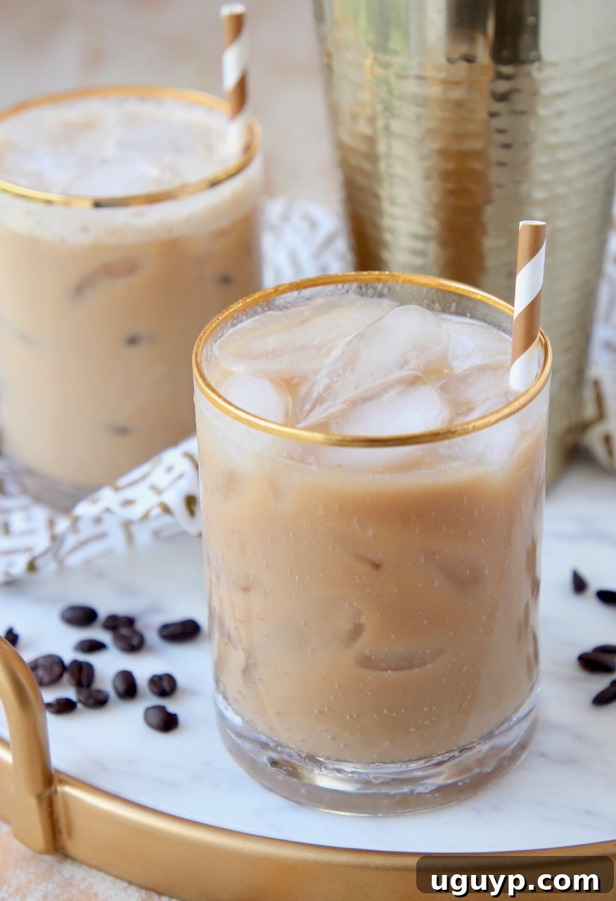 Two glasses of Long Island Iced Coffee drinks on a white marble serving tray, with a focus on the rich coffee color and elegant presentation.