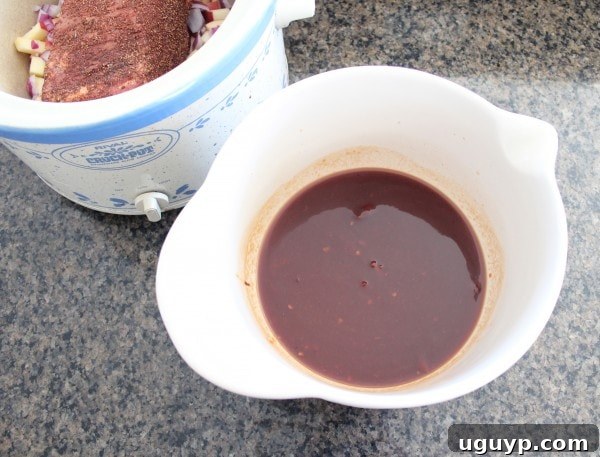 bowl of sauce sitting next to crock pot with seasoned brisket in it