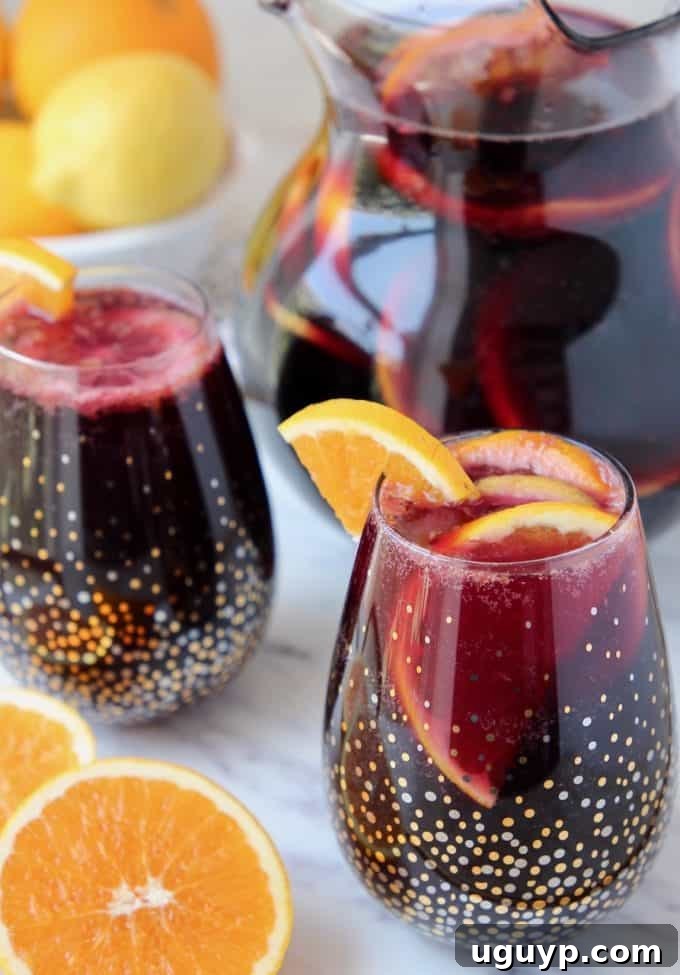 Red sangria in glasses and pitcher, garnished with fresh oranges and limes, ready to serve at a party.
