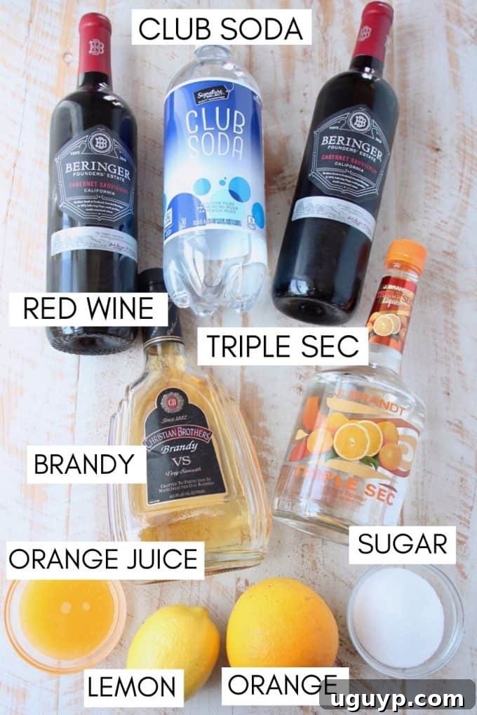 Ingredients for red sangria laid out: sliced oranges and lemons, sugar, bottles of red wine, brandy, triple sec, and orange juice.