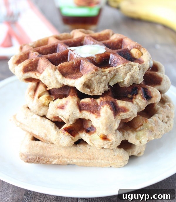 Gluten Free Peanut Butter Banana Waffles - A close-up of a plate with a waffle, a banana slice, and a fork.