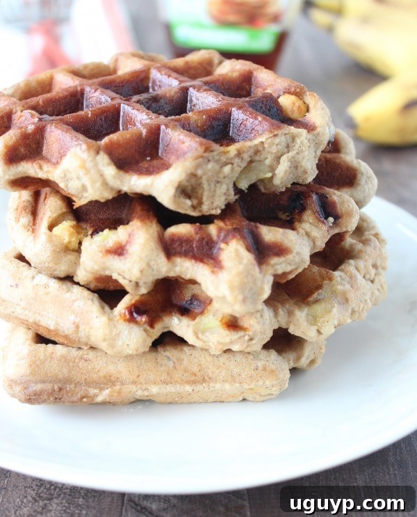 Crispy Banana Peanut Butter Waffles Stack - A stack of freshly made, golden waffles with a sprinkle of cereal and a banana slice.