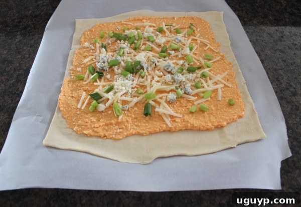 Spreading buffalo cheese mixture and toppings on puff pastry