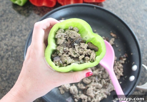 Bell peppers filled with seasoned ground turkey and mushroom mixture, ready for cheese