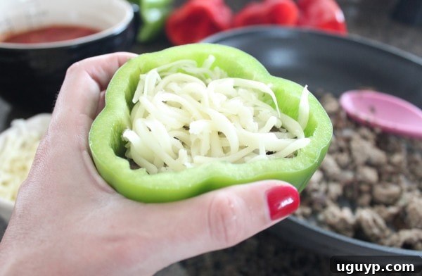 Stuffed bell peppers topped with shredded mozzarella cheese before cooking