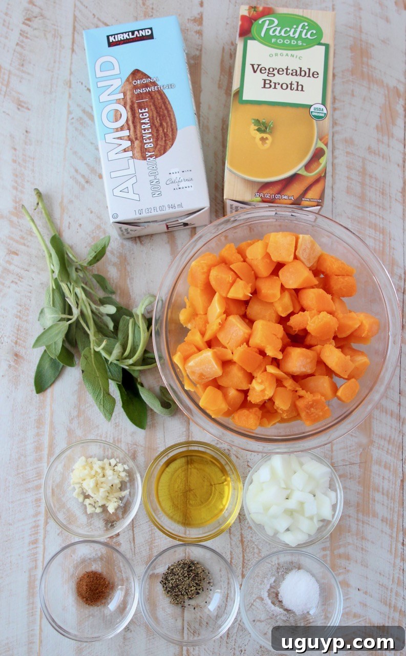 Fresh ingredients for butternut squash pasta sauce laid out on a white wooden board, including butternut squash, onion, garlic, sage, and spices.