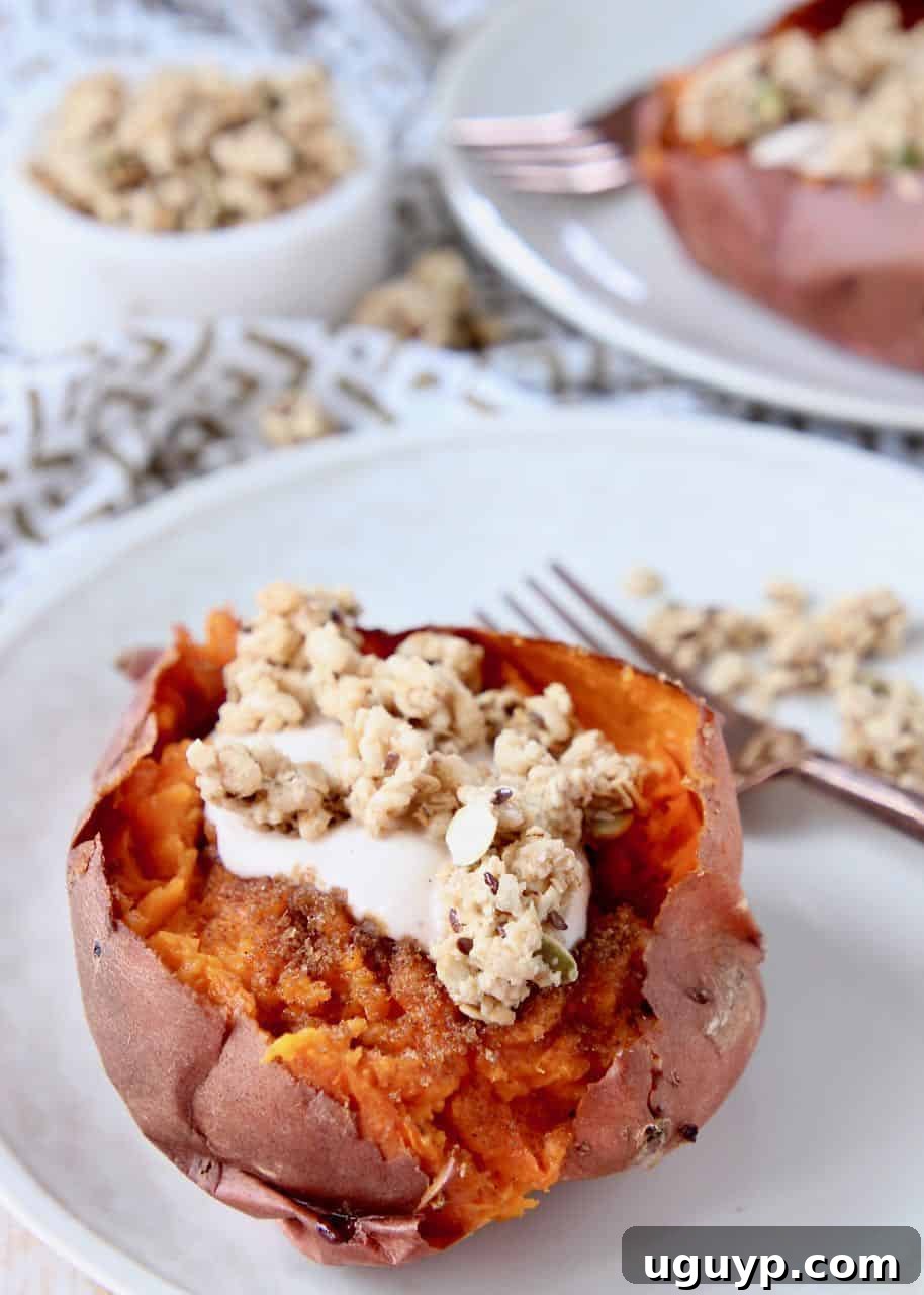 Roasted sweet potato on a plate, filled with yogurt and granola, garnished with a sprig of mint
