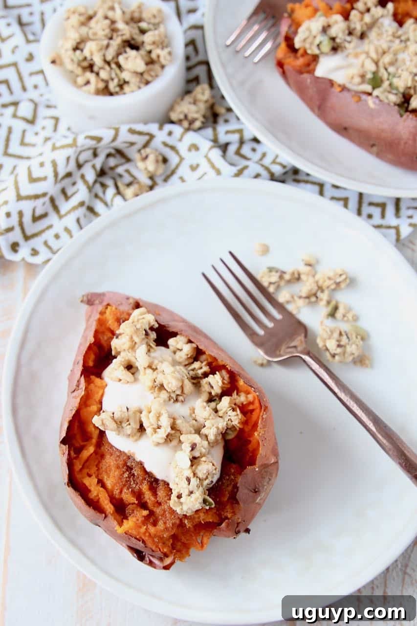 Roasted sweet potato sliced open and filled with yogurt and granola, ready to be served