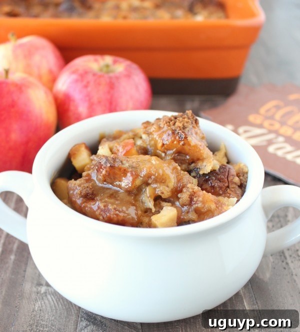Warm baked caramel apple bread pudding in a white serving bowl, garnished with a drizzle of caramel sauce.