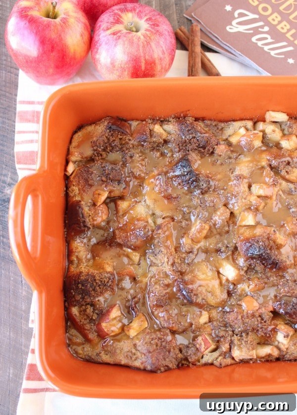 Baked bread pudding topped with a generous drizzle of caramel sauce in an orange baking dish, fresh out of the oven.