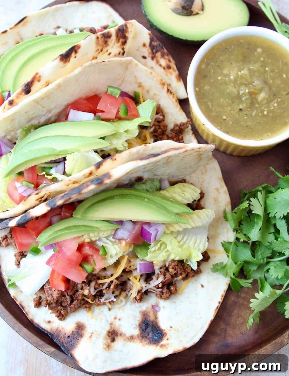 Tacos on wood tray with ramekin of salsa on the side