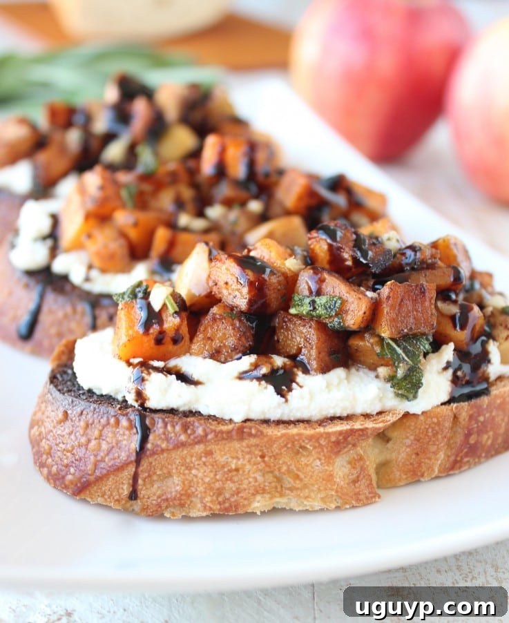 Delicious roasted diced butternut squash and spiced apples on top of creamy ricotta cheese, elegantly served on toasted artisanal bread, drizzled with balsamic glaze, making a perfect fall appetizer.
