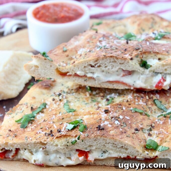 Golden-brown calzone, freshly baked and cut in half on a rustic wood cutting board, revealing its melted cheesy interior with pepperoni and vegetables.