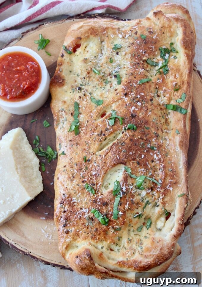 A beautifully baked, golden-brown calzone resting on a rustic wood serving board, ready to be sliced and enjoyed.