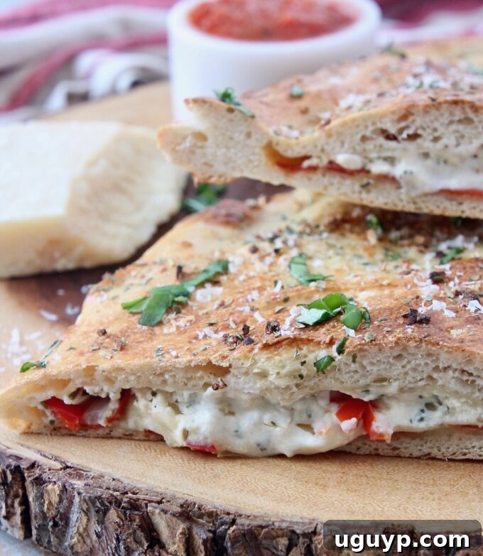 A freshly baked calzone, sliced open to reveal its rich, cheesy, and pepperoni filling, presented on a wooden cutting board.