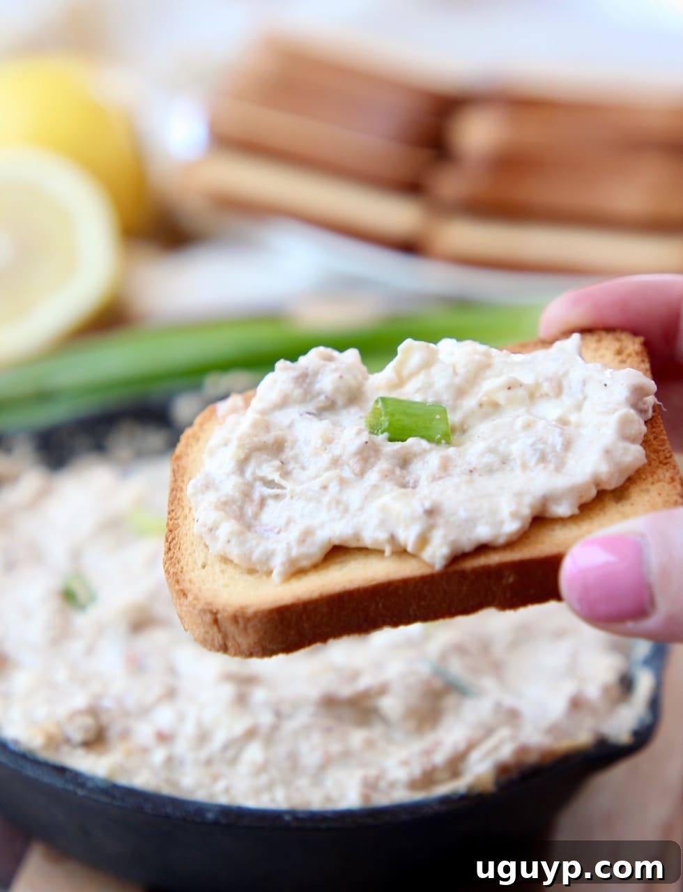 Hand holding brioche toast, topped with hot crab dip, close up