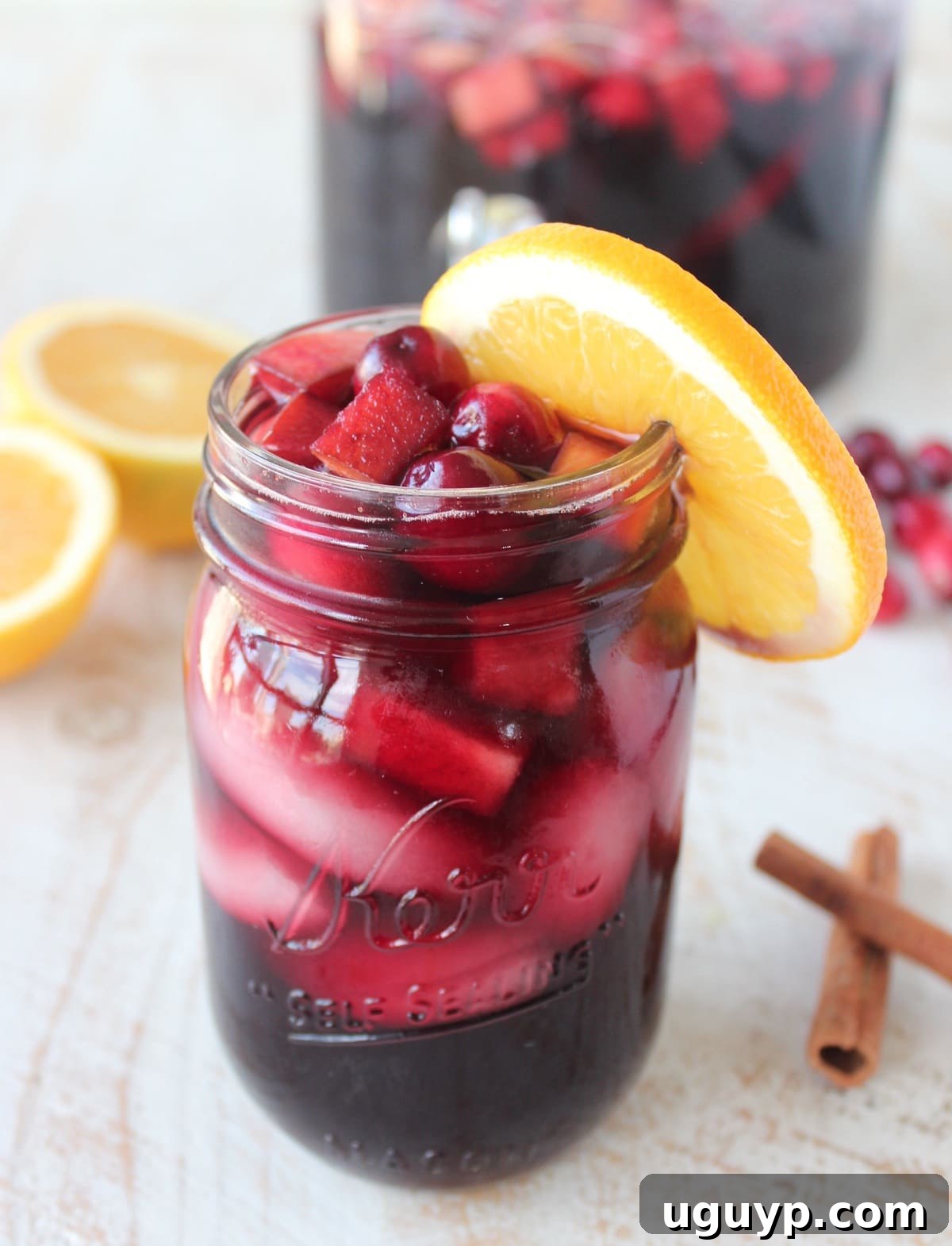 Cranberry Apple Sangria in a mason jar garnished with an orange slice and fresh cranberries, ready for fall celebrations