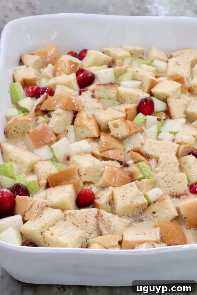 soaked bread cubes in a casserole dish with diced pears and cranberries