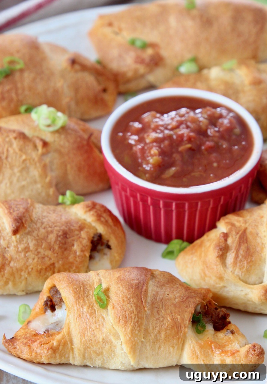 cooked taco filled crescent rolls on plate with bowl of salsa
