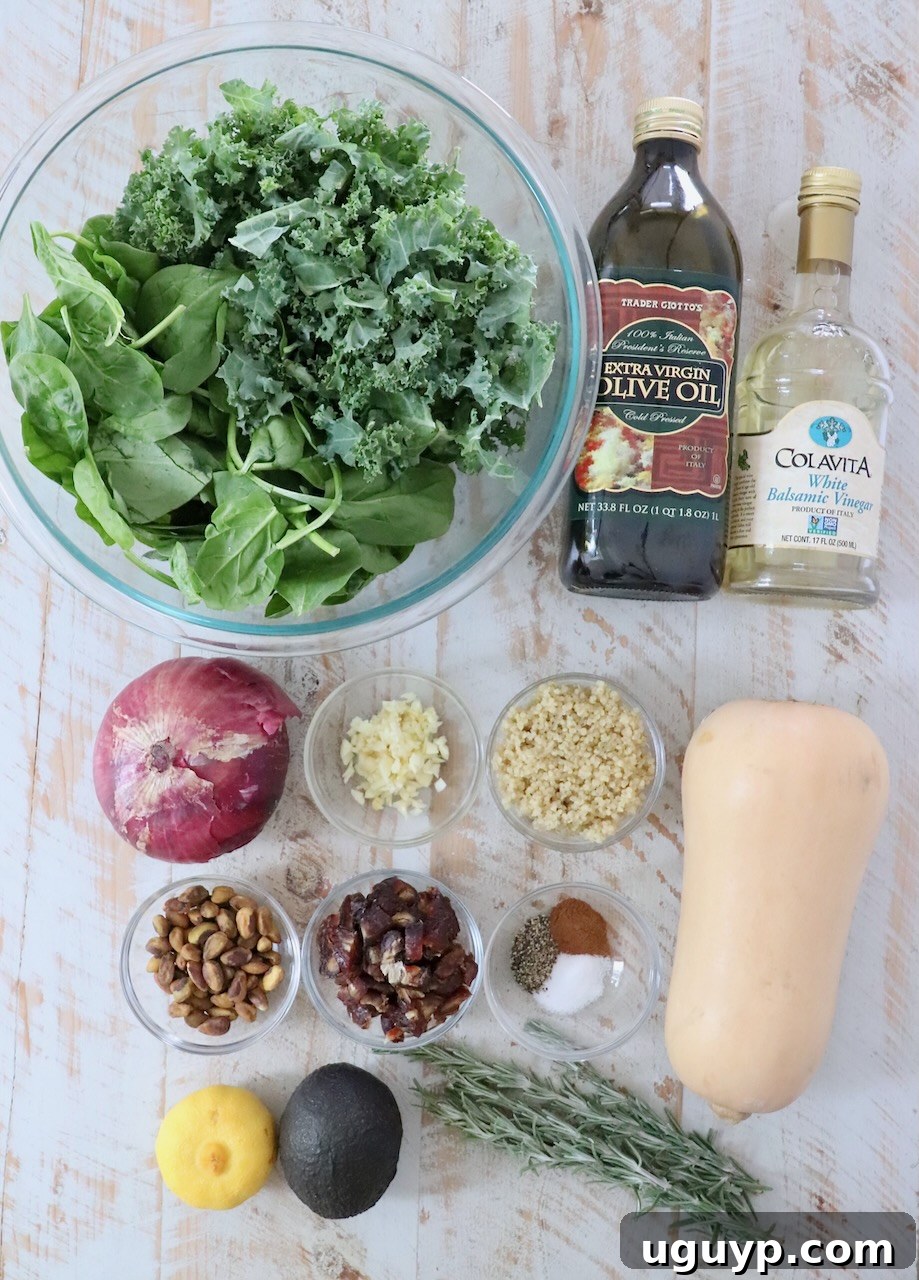 Assortment of fresh ingredients for butternut squash salad, including cubed squash, spinach, kale, dates, pistachios, and red onion, artfully arranged on a wooden board.