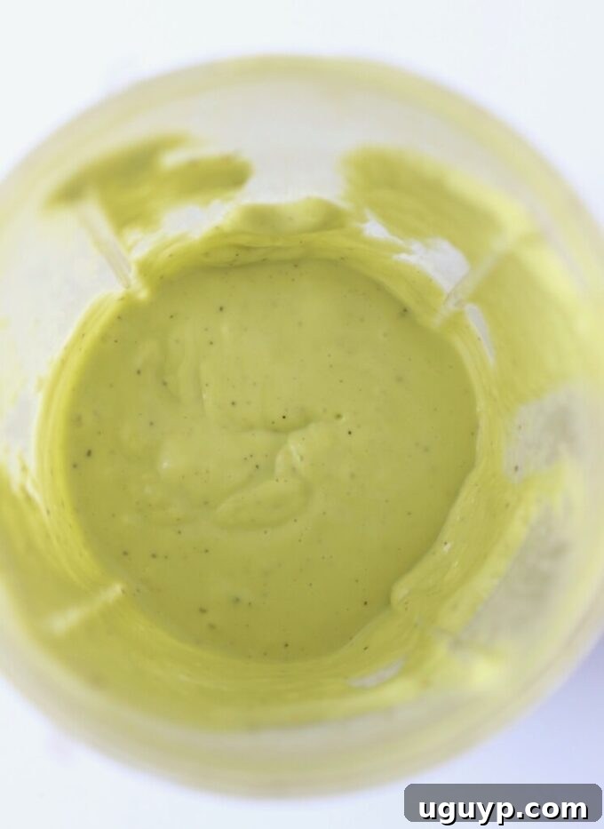 Smooth and creamy avocado vinaigrette dressing blended in a high-speed blender cup, showcasing its vibrant green color.