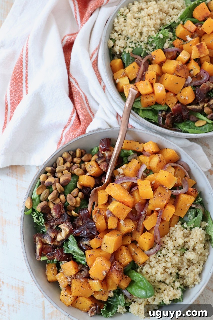 Two bowls of roasted butternut squash salad, each garnished with fresh greens and a fork, ready to be enjoyed.