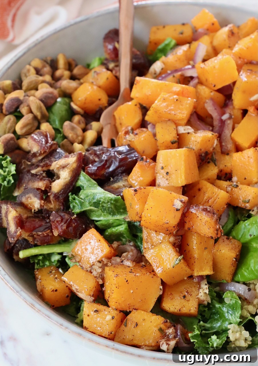 Close-up of roasted butternut squash salad, featuring tender squash, quinoa, greens, and pistachios, beautifully plated in a ceramic bowl.