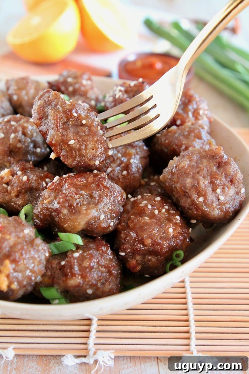 Chinese Meatballs in bowl, with gold fork holding up one meatball