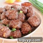 Chinese orange glazed meatballs in bowl with sesame seeds and green onions on top