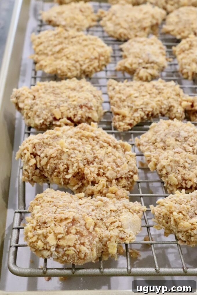 Uncooked breaded pieces of chicken on a wire rack on top of a baking sheet