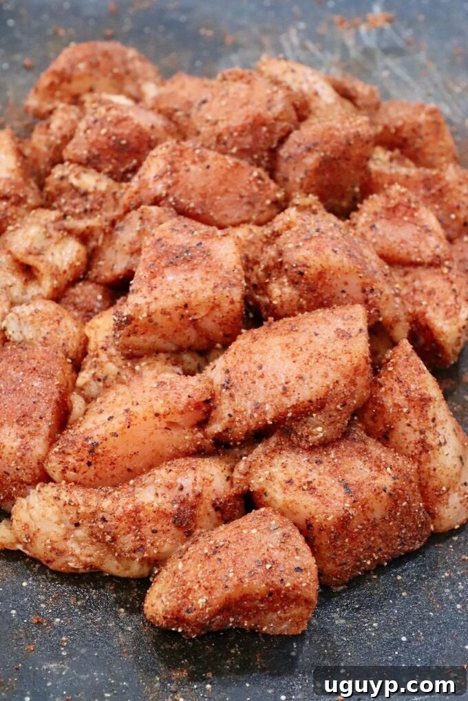 Seasoned raw cubes of chicken on a cutting board