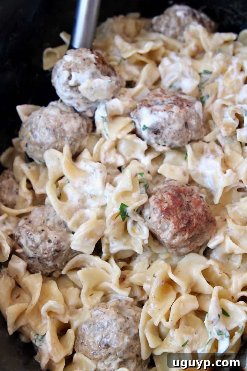 Slow Cooker Swedish Meatballs and egg noodles cooking in a crockpot