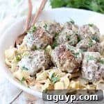 Swedish meatballs in bowl with cooked egg noodles and copper forks