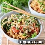 A vibrant and comforting bowl of Thai peanut noodles with chopsticks resting on the side, inviting you to dig in.