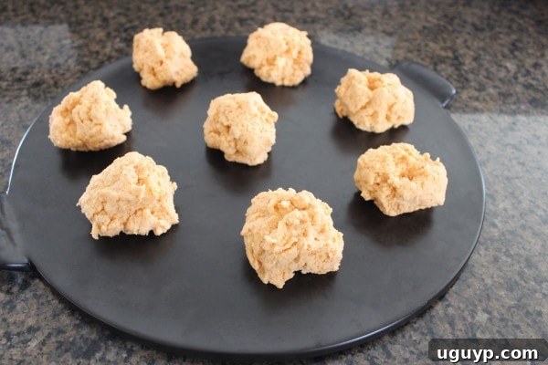 biscuit dough dolloped on a black round baking stone