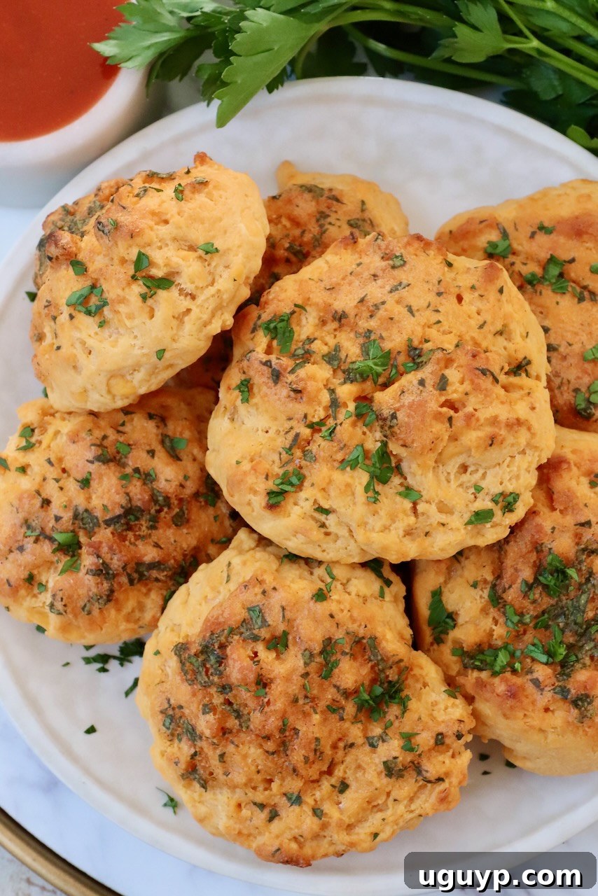cheddar biscuits stacked up on a plate with fresh parsley