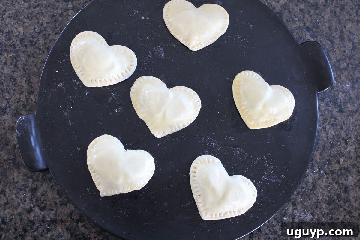 Heart Shaped Strawberry Cheesecake Puff Pastry Pies on a baking sheet, brushed with egg wash